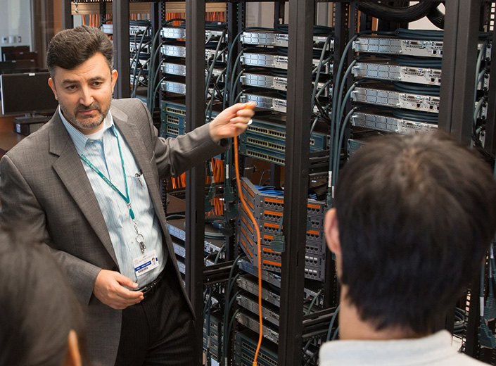 Dr. Wael demonstrates Computer networking in a server room to a small group of students.