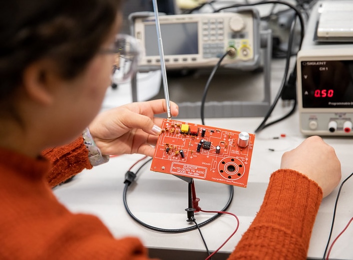 Female Mechatronics students works with a circuit board.