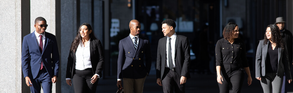 Students in black and blue Business attire walk together during a Year Up event. 